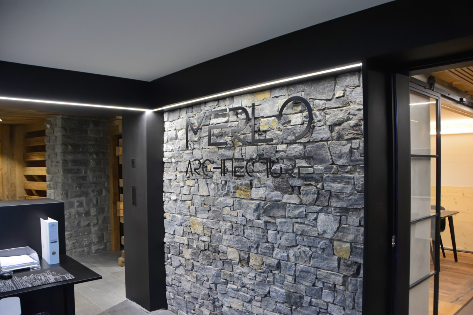 Interior by MERLO Architecture, stone wall and dark joinery